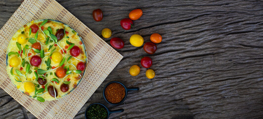 Obraz na płótnie Canvas Homemade veggie pizza with cherry tomatoes and other ingredients on a wooden background