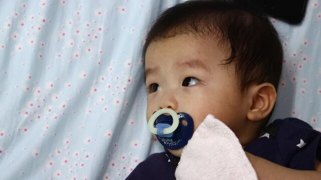 Local lifestyle of 8 Month Chinese baby boy sucking pacifier ready to sleep