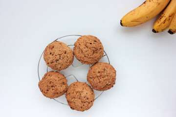 Oatmeal banana cookies on white table. Overhead view of oat biscuits and yellow fruits on white background with copy space