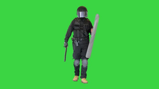 Heavily armored policeman with a shield and a baton walking on a Green Screen, Chroma Key.