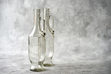 Two transparent glass bottles with handles on a gray-white textured background. Copy space.