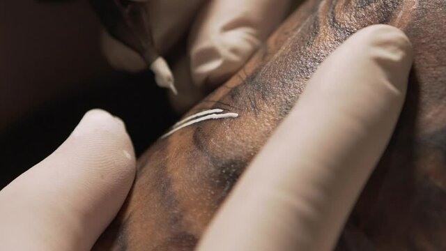 Crop master making tattoo on skin of client