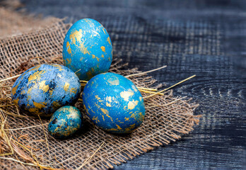 Easter decoration concept: blue painted eggs on the sackcloth with hay close-up