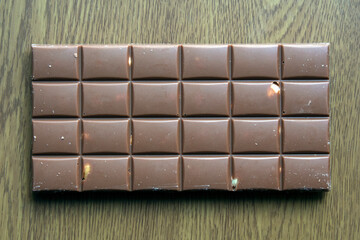milk chocolate bar with hazelnuts on wooden background. top view