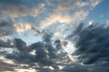 Beautiful fluffy clouds in the evening sky. The sunlight gives a side light on the clouds. Clouds before rain.