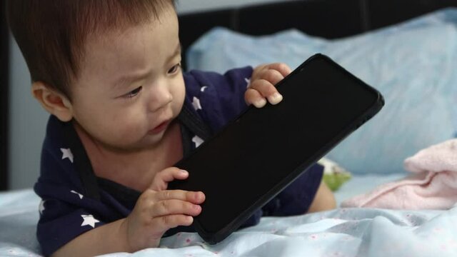 8 Month old baby boy wanna play Smartphone while lying on bed.