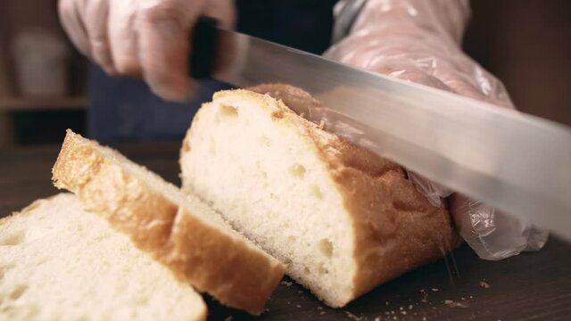 Male hands slicing bread, close-up. Chef complies with safety measures during the Covid-19 pandemic using antibacterial gloves.