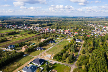 Luftaufnahme über Dorf und Wälder bei blauen Himmel mit Wolken