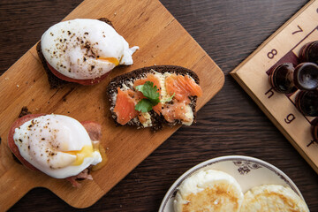 Sandwiches with red salmon and poached eggs near chessboard game