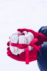 White eclair (Traditional French dessert) mini-cake with red ribbon. A woman with red gloves is...