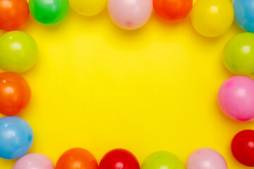 Colorful balloons and confetti on yellow table top view. Festive or party background. Flat lay style. Birthday greeting card. Carnival.