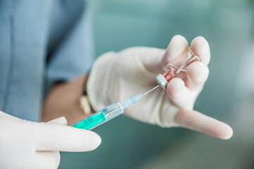 Sanitaria con guantes introduciendo la vacuna en el vial