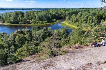 Russia, Lake Ladoga, August 2020. A couple of tourists on a granite rock above the lake.