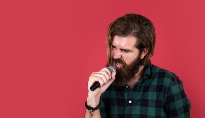 Fototapeta na wymiar man singer love music. brutal man sing with microphone. vocal school. brutal and rock. bearded man wear checkered shirt singing song. male singer with mic. concept of karaoke. copy space