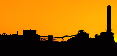 Industrial cement plant silhouette during sunset