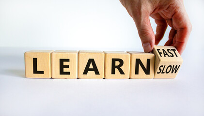 Learn slow or fast symbol. Businessman turns wooden cubes and changes words 'learn slow' to 'learn fast'. Beautiful white background, copy space. Business and learn slow or fast concept.