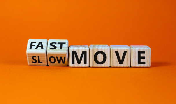 Time to fast move symbol. Turned wooden cubes and changed words 'slow move' to 'fast move'. Beautiful orange table, orange background, copy space. Business and slow or fast move concept.