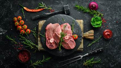 Raw boneless lamb steak with rosemary and spices. On a dark background. Top view.