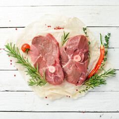 Meat. Raw boneless lamb steak with rosemary and spices. On a white wooden background. Top view.