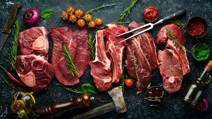 Set of raw beef and veal steaks. Meat. Top view. Flat lay top view on black stone cutting table.