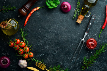 Fototapeta na wymiar Black stone cooking background. Spices and vegetables. Top view. Free space for your text.