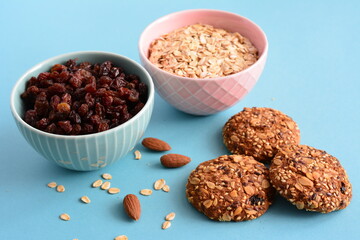 two bowls with raisin and oatmeal and oat cookies on the blue background