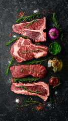 Variety of raw black Angus Prime meat steaks: t-bone, striploin, Rib eye, new york steak. Top view....