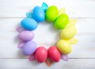 Easter colorful eggs in the form of a wreath on a light wooden background. Easter concept.