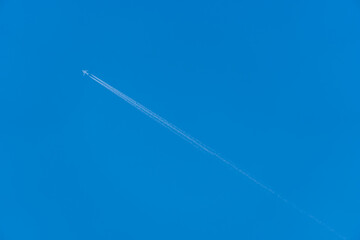 Airliner with vapour trail against a blue sky.	
