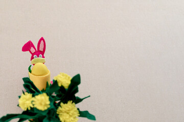 Pink bunny  stand with face mask, styrofoam yellow Easter egg on a beige background. The concept of...
