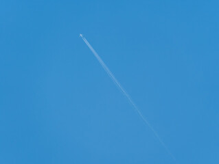 Airliner with vapour trail against a blue sky.