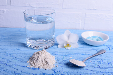Collagen protein powder  and water in glass  on blue background, healthy lifestyle concept