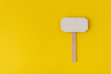 Wooden pointer on yellow background. Information plate. Wooden plate. Copy space. Mock up