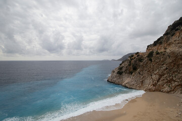 Wide angle seascape with hill,  waves, turquoise sea and  beach 