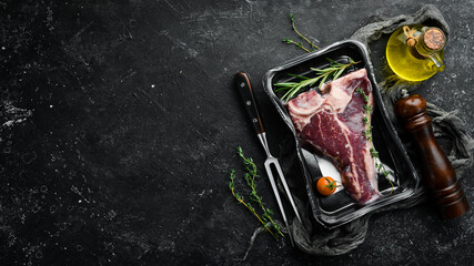 Obraz na płótnie Canvas T-bone steak in vacuum packaging. Market. Top view. Flat lay top view on black stone cutting table.