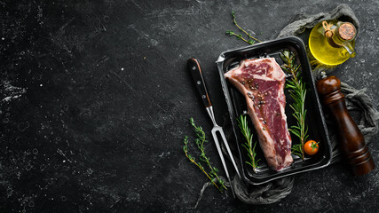 Veal Steak "New York" in vacuum packaging. Market. Top view. Flat lay top view on black stone cutting table.