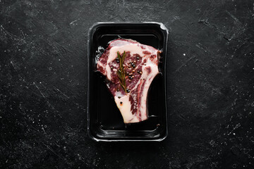 Ribeye beef steak in vacuum packaging. Market. Top view. Flat lay top view on black stone cutting table.