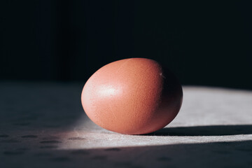 Brown egg with hard shadow on table. Creative Easter Christian tradition concept