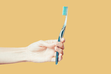 Female hand holding toothbrush with toothpaste isolated on black background. Oral care, dental hygiene concept.