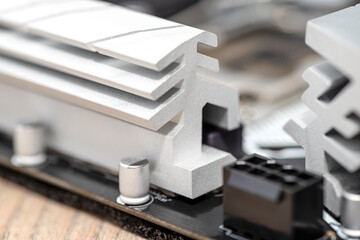 Macro shot of a silver heat sink dissipating heat from the power section on the motherboard of a desktop computer.