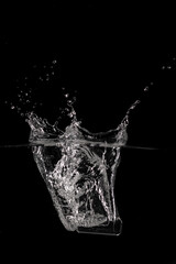Vial of medicine (coronavirus vaccine) falling into water with splashes and bubbles