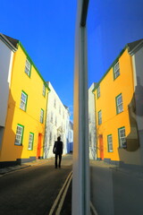 Silhouette of alone man passing colorful buildings reflected in mirror