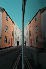 Silhouette of alone man passing colorful buildings reflected in mirror