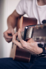 Detail on the artist's fingers as they flick over the instrumental instrument to make the right sound. Business as usual. A middle-aged man plays his guitar and sings along. Music lesson