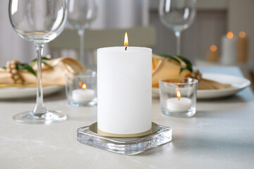 Obraz na płótnie Canvas White burning wax candle on light table