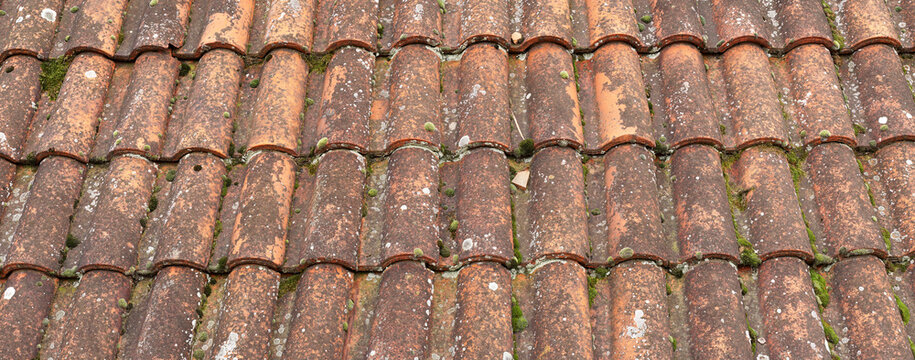 Old roof tiles. House roof with old weathered dirty red tiles. Vintage tiles as background. High resolution background. Panoramic image, hi-res banner.