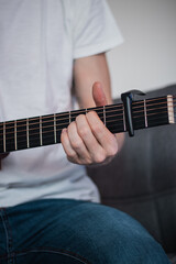 Fototapeta premium part of a wooden guitar and the hand of a singer who changes holding the guitar according to the chord he needs. Special handle for adjusting the tone. Learning new skills during quarantine