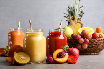 Delicious juices and fresh ingredients on grey table