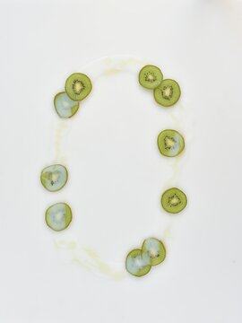 white background of spilled body milk with kiwi and oil