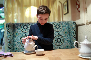 Boy pouring tea in restaurant